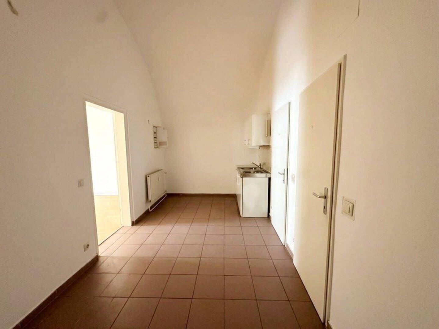 Kleine Küchenzeile mit Spüle und Fliesenboden in einem funktionalen Raum.