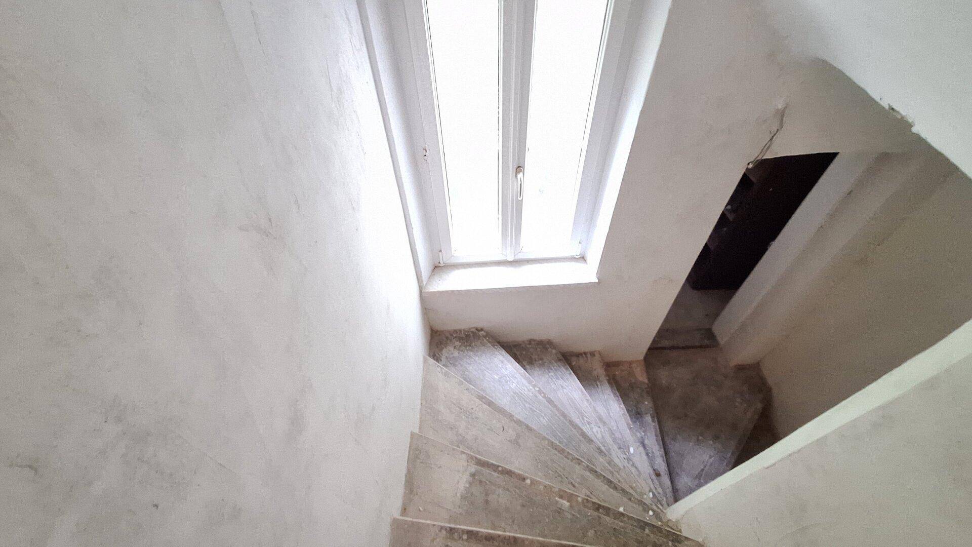Treppenhaus von oben gesehen mit einem Dachfenster, das natürliches Licht spendet.