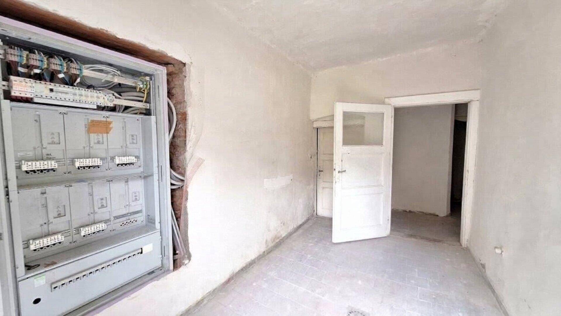 Raum mit offenem Sicherungskasten und vorbereiteten Wänden für weitere Arbeiten.