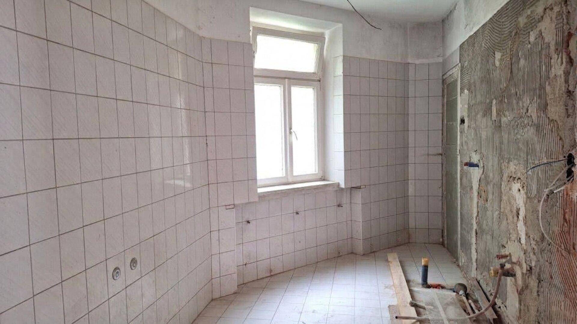 Küche in Renovierung mit gefliesten Wänden und Boden, bereit für die Installation neuer Geräte.
