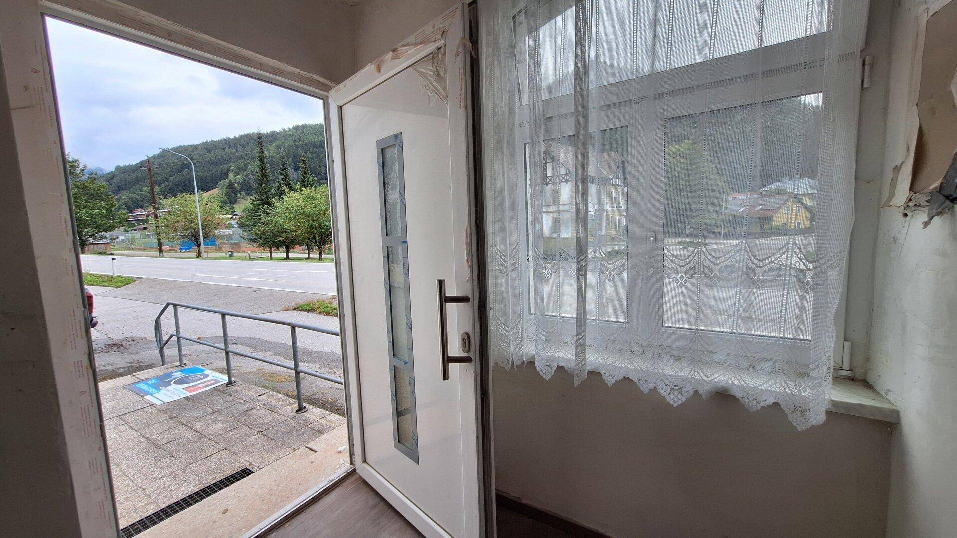 Eingangsbereich mit offener Tür, die den Blick nach draußen auf die Straße freigibt.