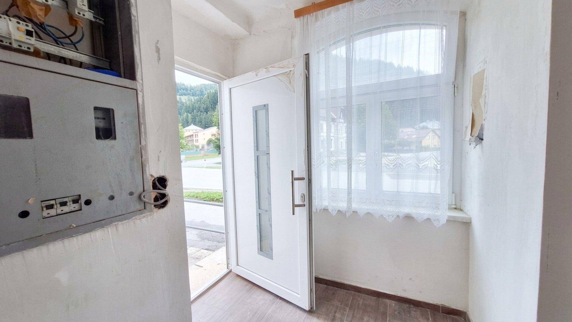 Eingangsbereich mit offener Tür, Fenster und sichtbarem Sicherungskasten.