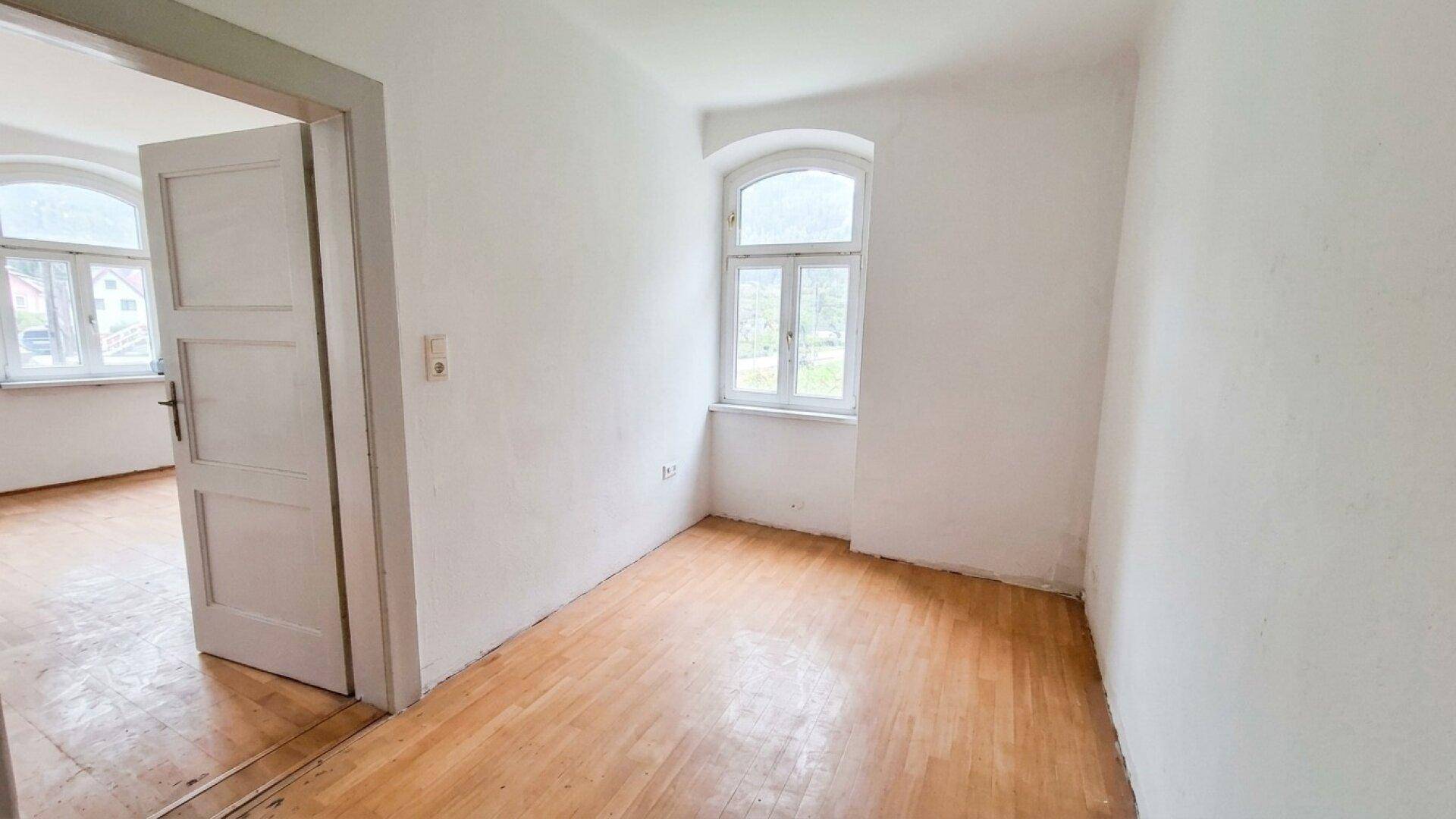 Kleiner Raum mit Holzboden und einem Rundbogenfenster, bereit zur individuellen Gestaltung.