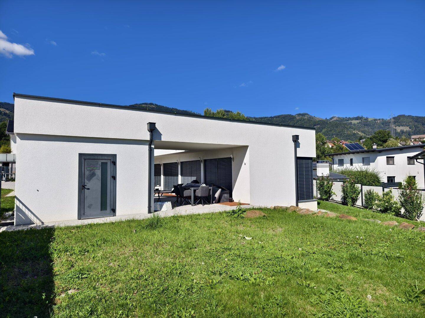 Überdachte Terrasse mit Gartenmöbeln und Blick auf die grüne Hügellandschaft.