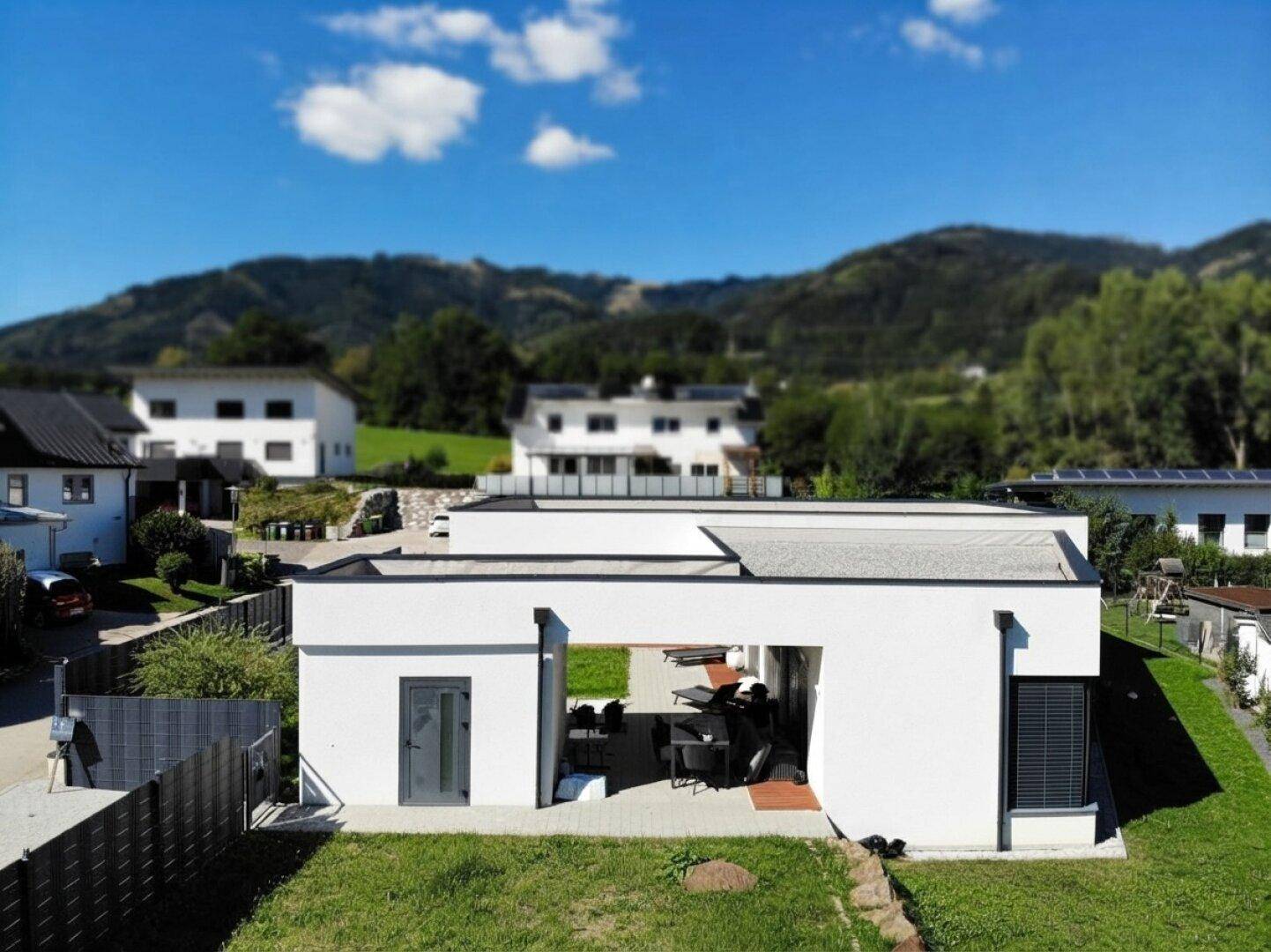Luftaufnahme des modernen Hauses mit überdachter Terrasse und weitem Blick auf die umliegende Natur.