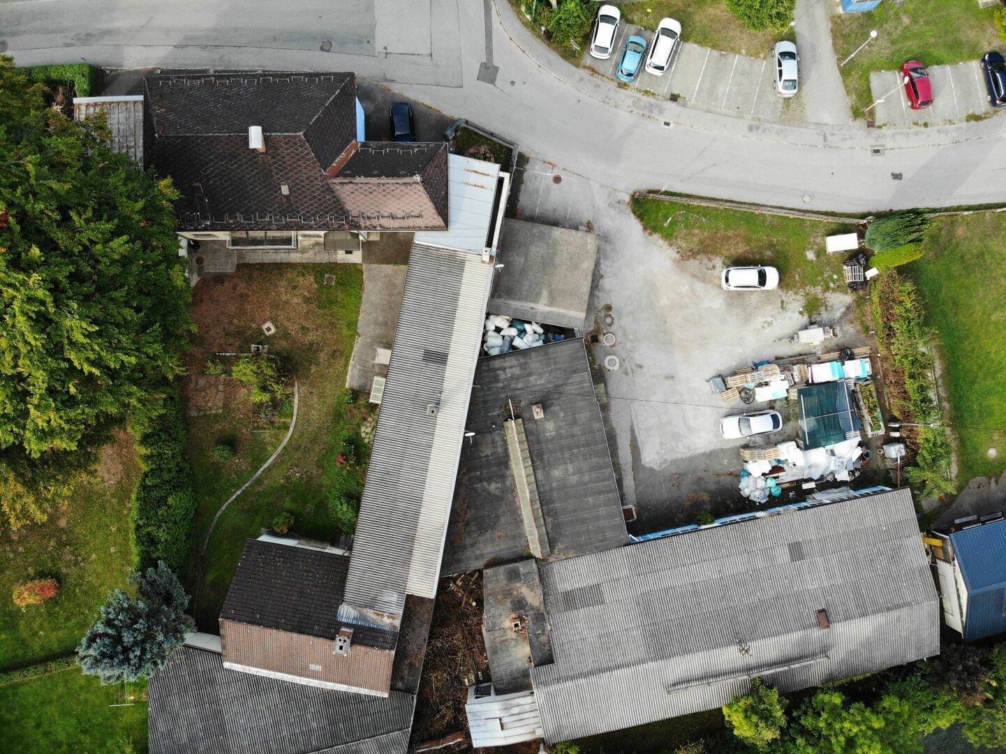 Draufsicht des gesamten Gebäudekomplexes mit verschiedenen Dächern, Straßen und Parkflächen.