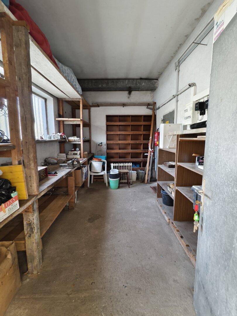 Lagerraum oder Werkstatt mit Betonboden und praktischen Holzregalen für Stauraum.