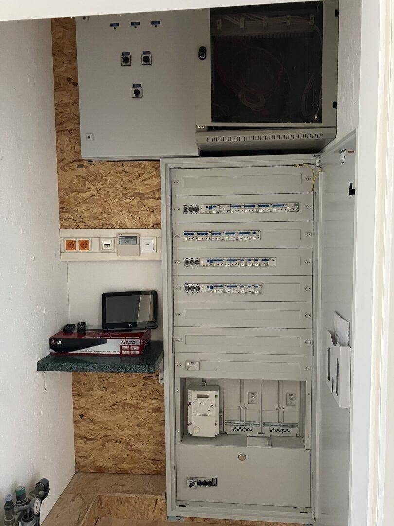 Hauswirtschaftsraum mit mehreren Elektroschalttafeln und einem Regal für technische Geräte.
