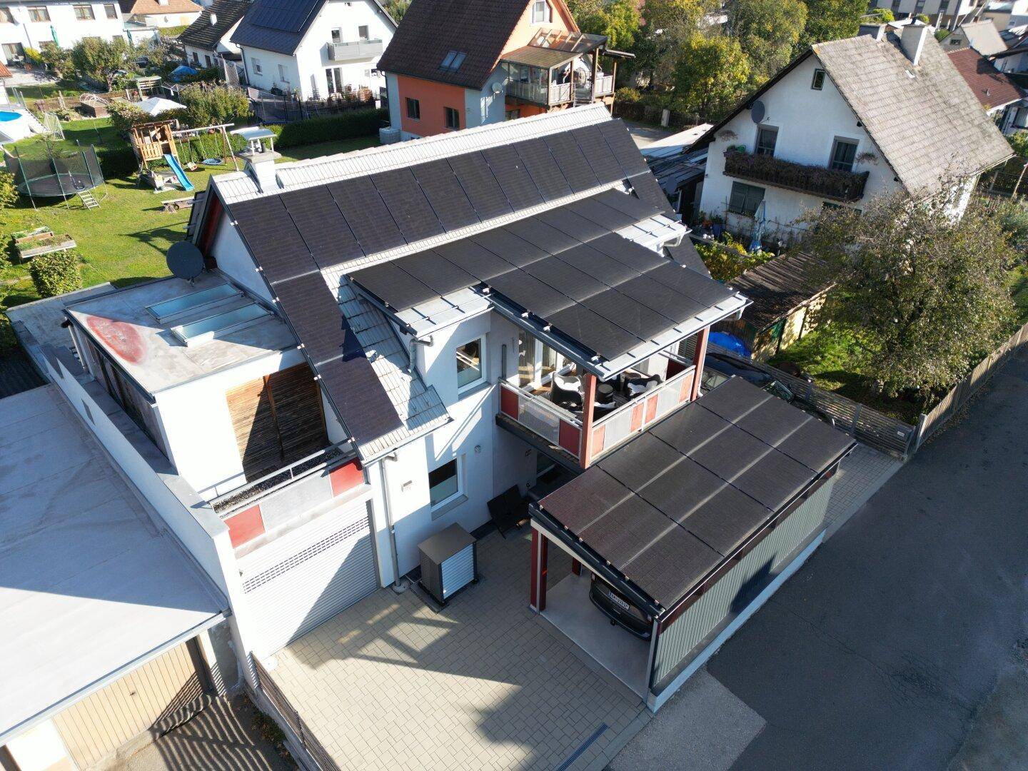 Luftaufnahme des Hauses mit Photovoltaikanlage auf dem Dach und umliegenden Gärten in der Nachbarschaft.