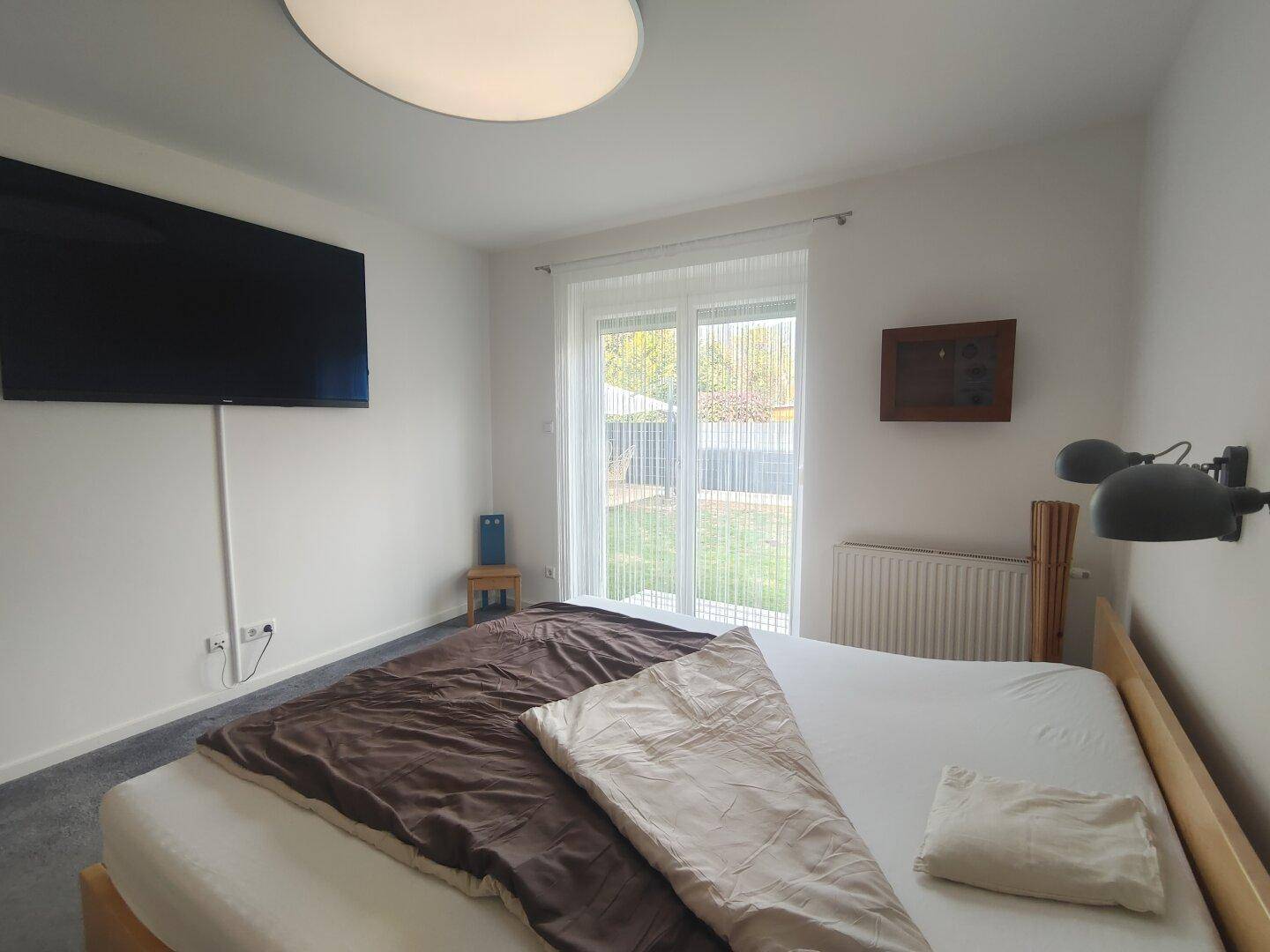Gemütliches Schlafzimmer mit Doppelbett, Teppichboden und direktem Zugang zum Gartenbereich.