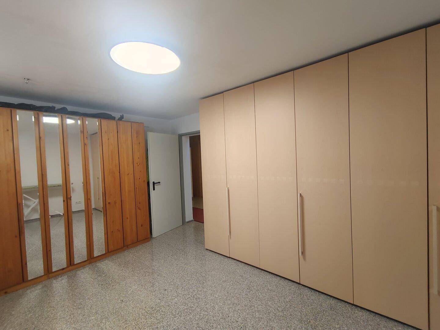 Geräumiges Schlafzimmer mit Einbauschränken, Teppichboden und Oberlicht für zusätzliche Helligkeit.