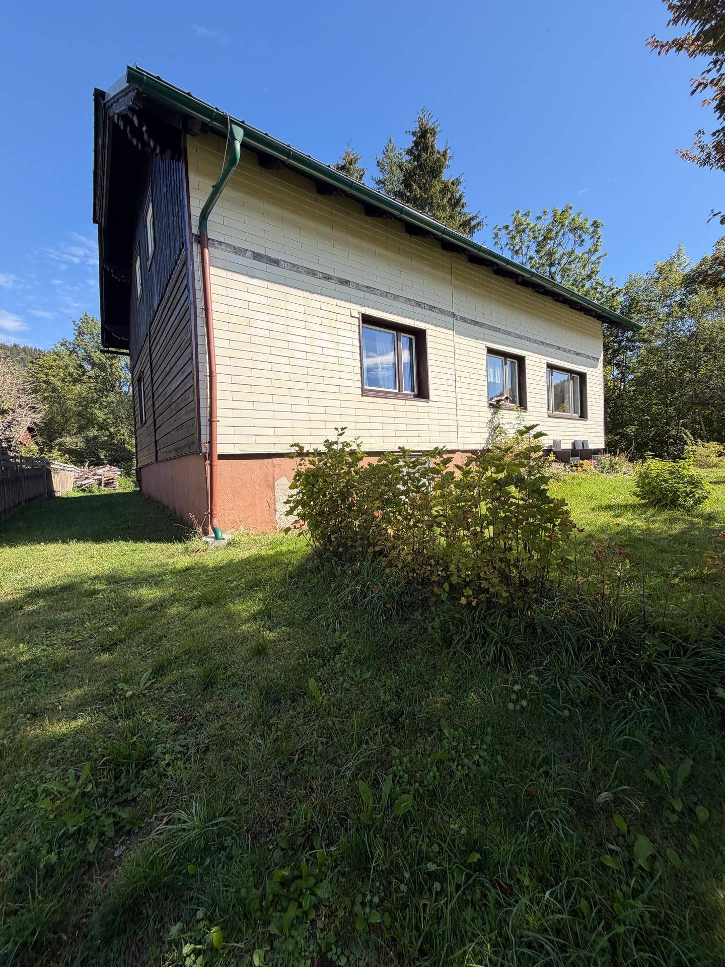 Seitenansicht des Hauses mit Holzverkleidung und umgebender Natur.