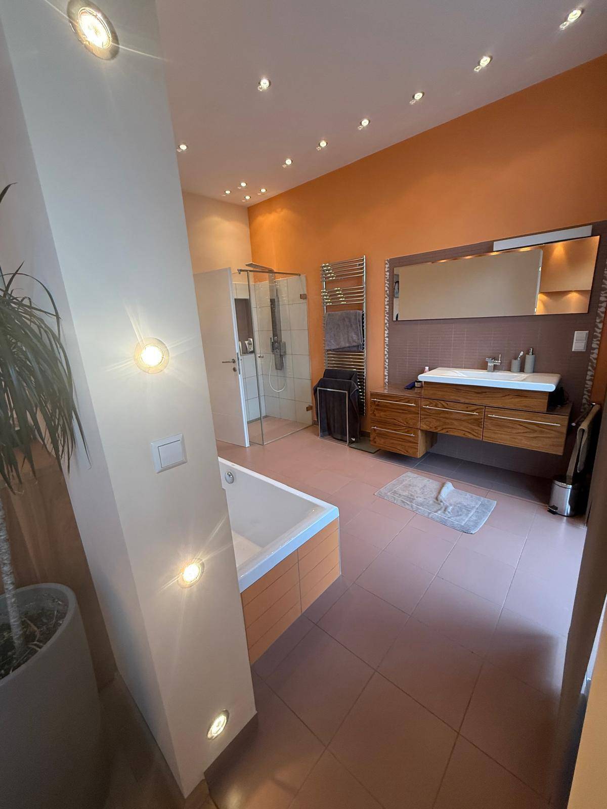 Elegantes Badezimmer mit Badewanne, Dusche, modernem Waschtisch und indirekter Beleuchtung.