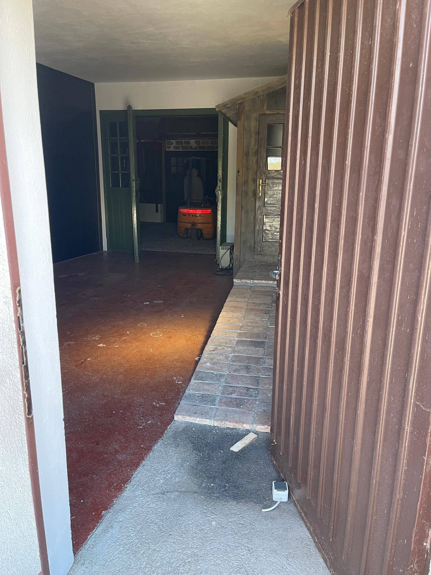 Innenraum mit Rampe, Ziegelfliesen und einem Gabelstapler, der auf einen weiteren Bereich blickt.