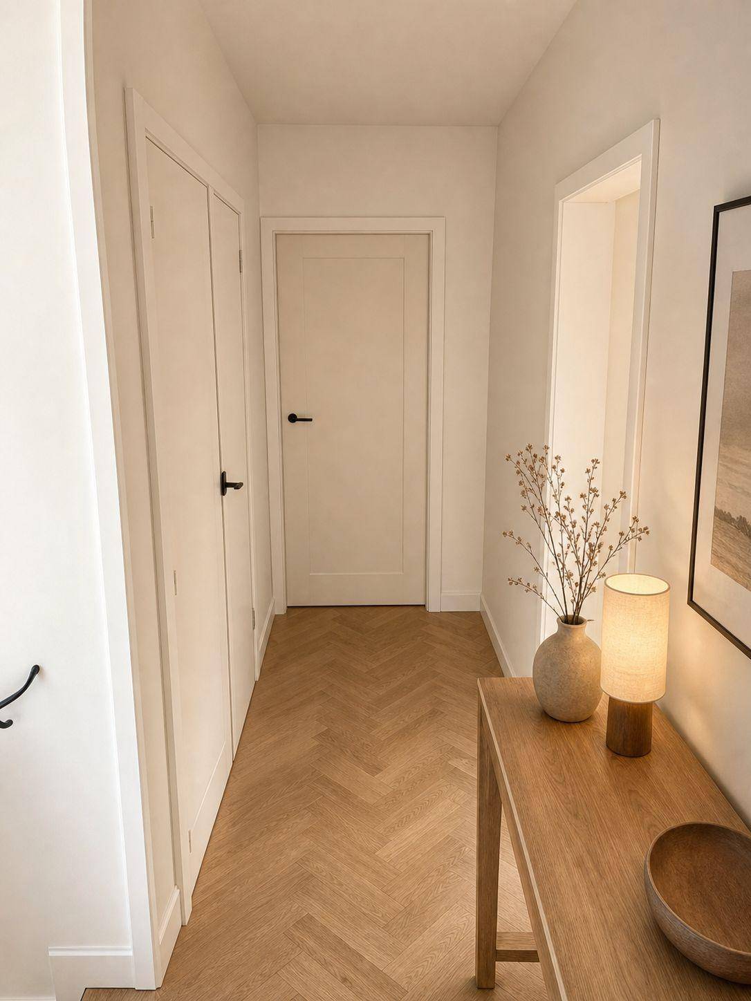 Heller Flur mit elegantem Fischgrätparkett und modernen weißen Türen.