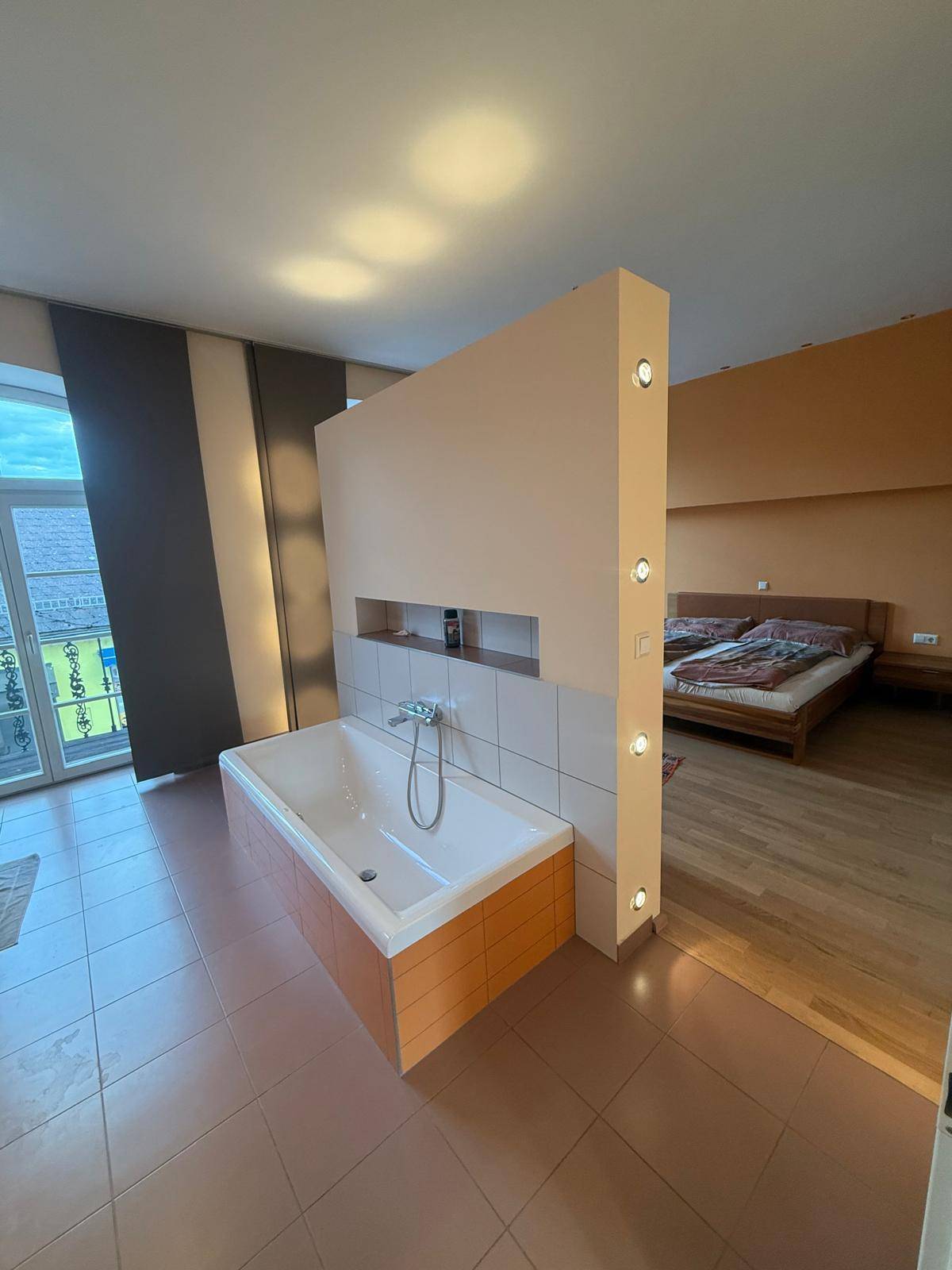 Offenes Badezimmer mit Badewanne, das elegant in den Schlafbereich integriert ist.