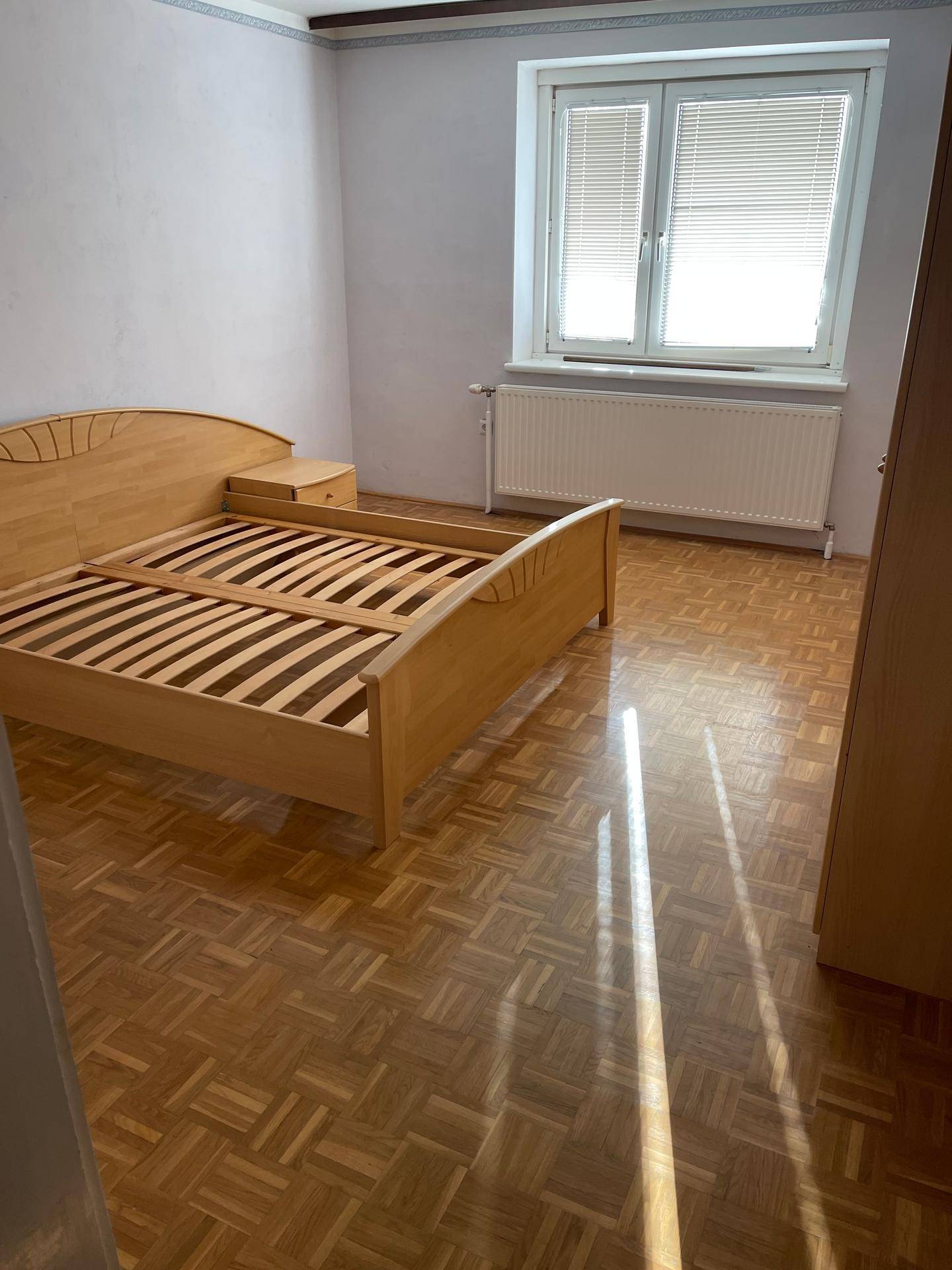 Schlafzimmer mit Parkettboden und einem Holzbettgestell.
