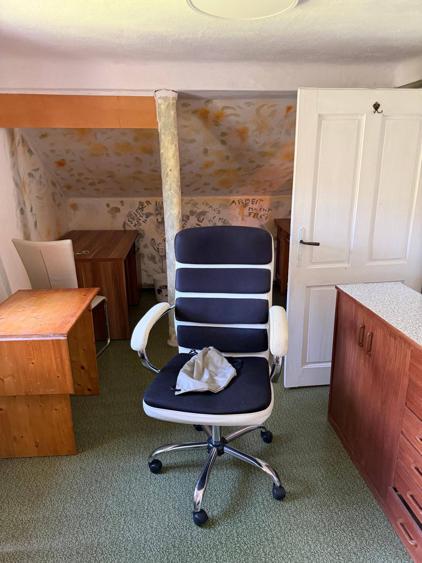 Büro im Dachgeschoss mit Teppichboden, Schreibtisch und Bürostuhl.