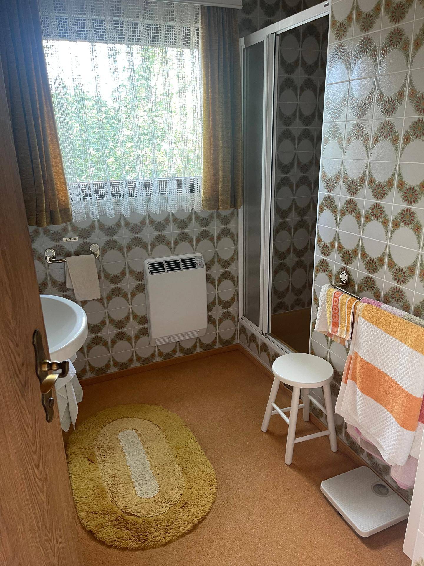 Badezimmer im Stil der 80er Jahre mit gemusterten Fliesen, Dusche und Teppichboden.