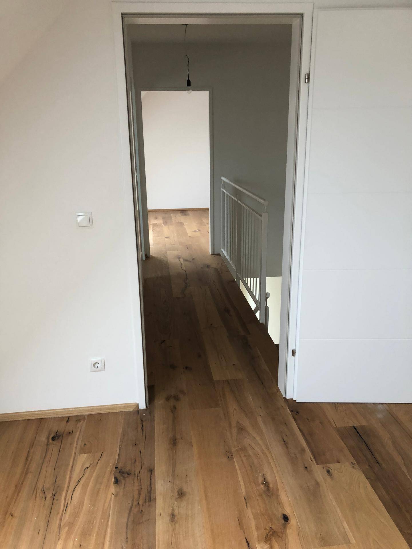 Heller Flur mit Holzboden, der zu weiteren Zimmern und einer Treppe führt.