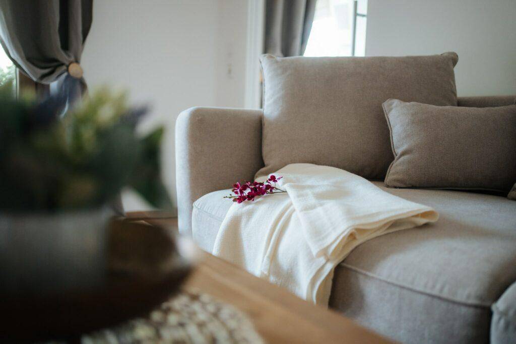Nahaufnahme eines bequemen Sofas mit Kissen und Decke, lädt zum Verweilen ein.