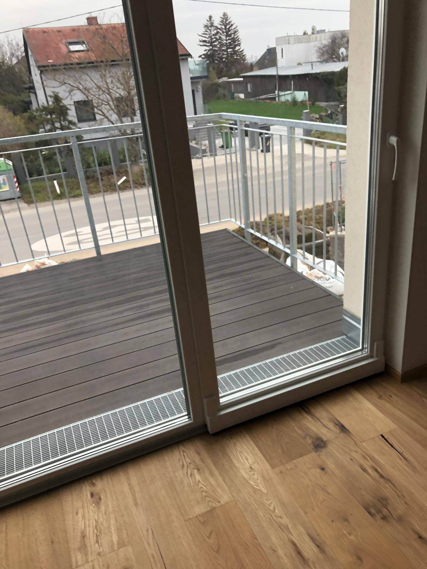 Moderner Balkon mit Holzdielen und Blick auf die Straße und die Umgebung.