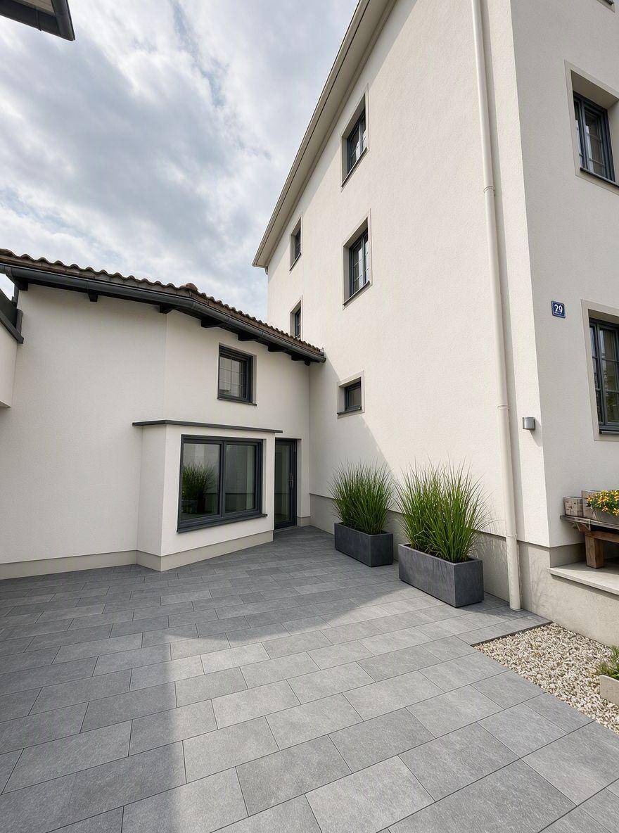 Gepflasterter Innenhof mit modernen Pflanzkübeln und Zugang zum Gebäude.