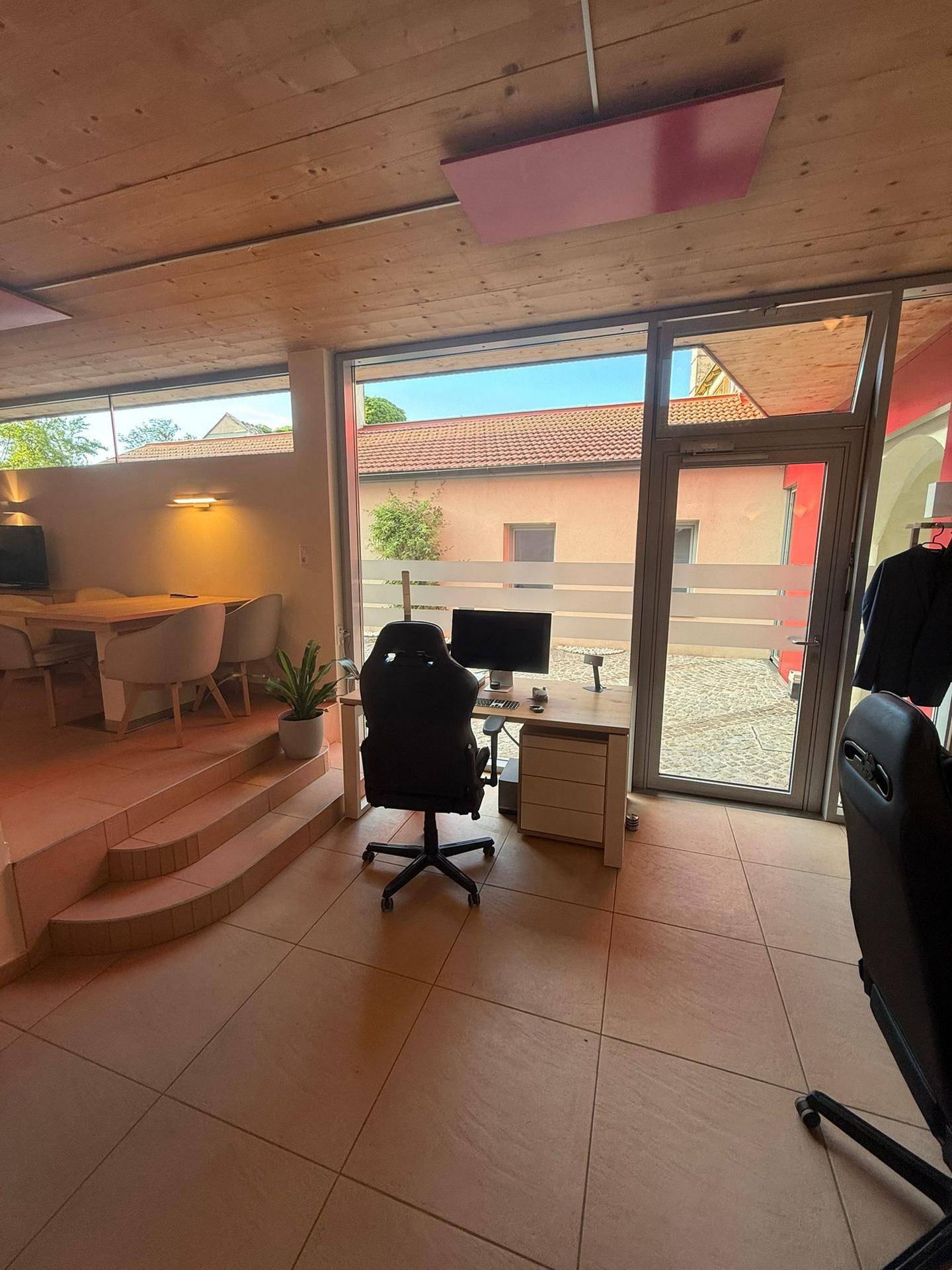 Helles Büro mit großen Fenstern, die viel Tageslicht hereinlassen, und Zugang nach draußen.