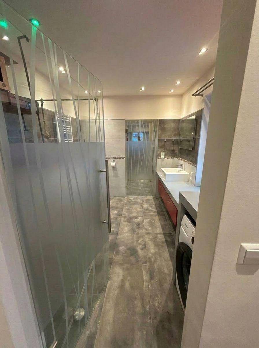 Modernes Badezimmer mit begehbarer Dusche und langem Waschtisch mit Einzelwaschbecken.