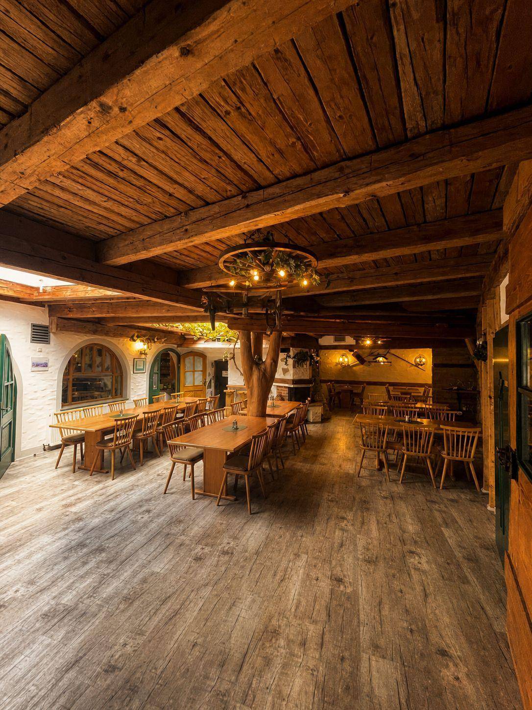 Großer Essbereich mit Holzbalkendecke, Holztischen und Stühlen, rustikales Ambiente.