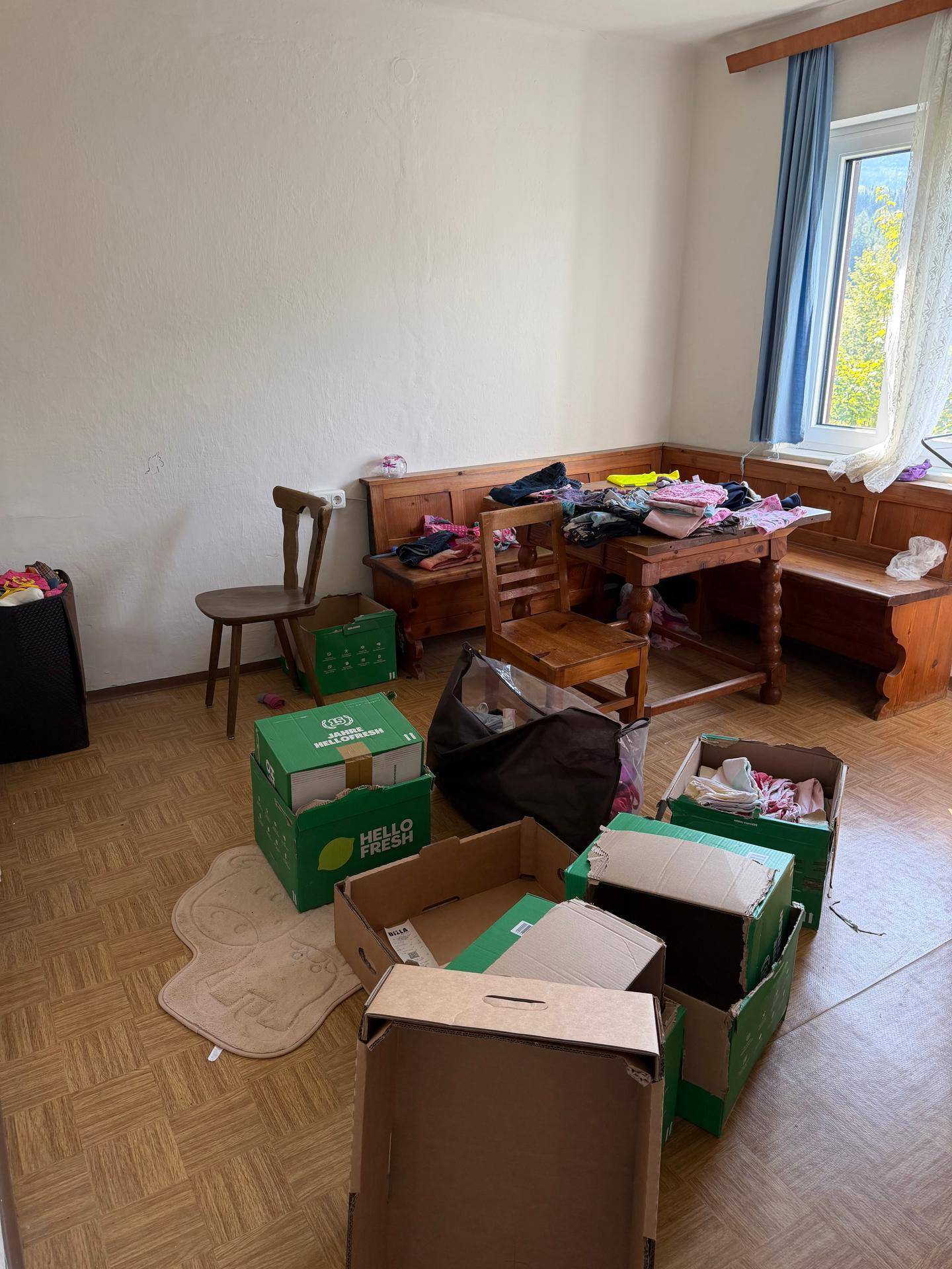 Wohnzimmer mit traditionellen Holzmöbeln, Parkettboden und Blick ins Grüne.