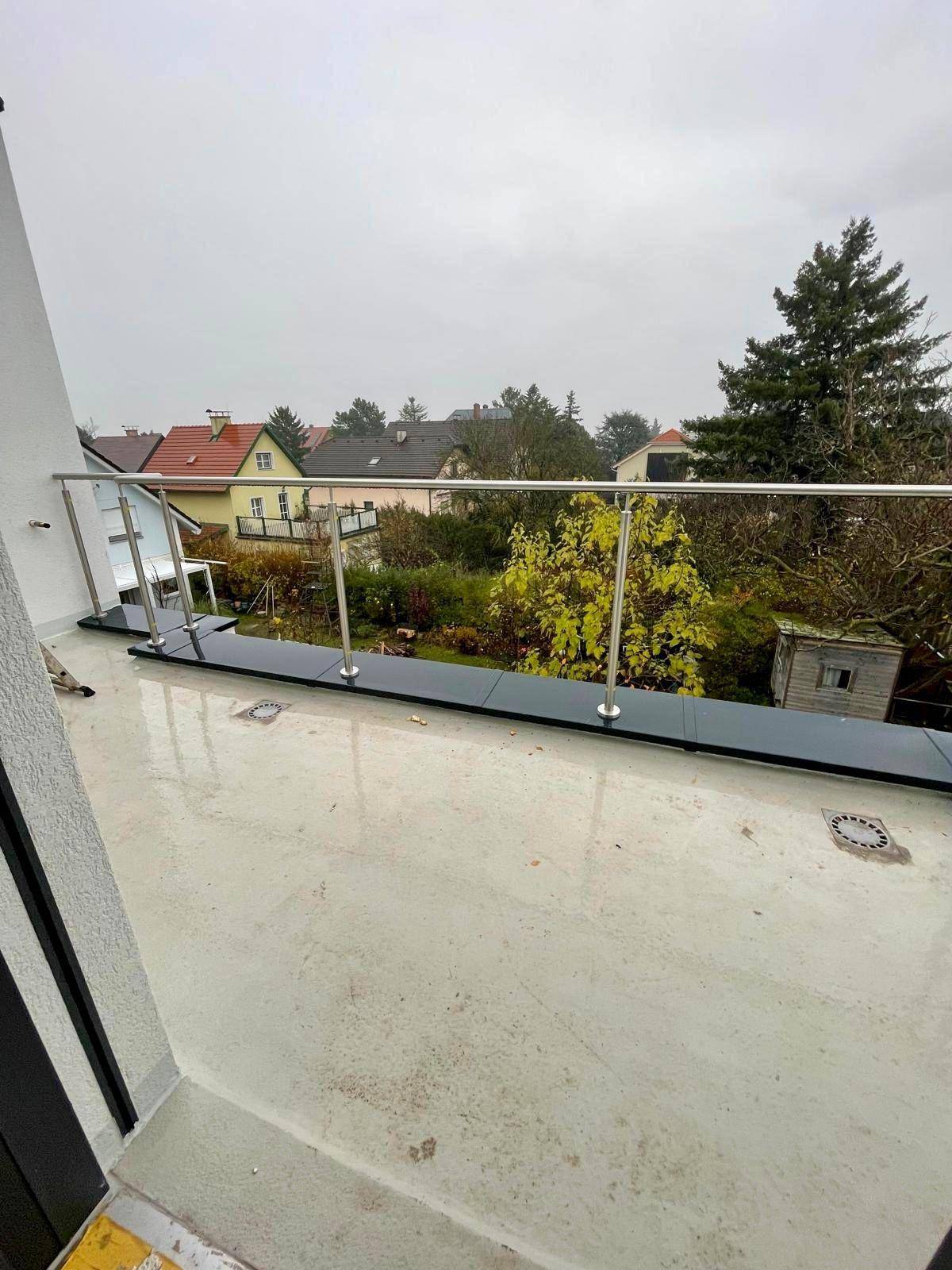 Weitläufige Terrasse mit Glasgeländer und Panoramablick über die grüne Umgebung.