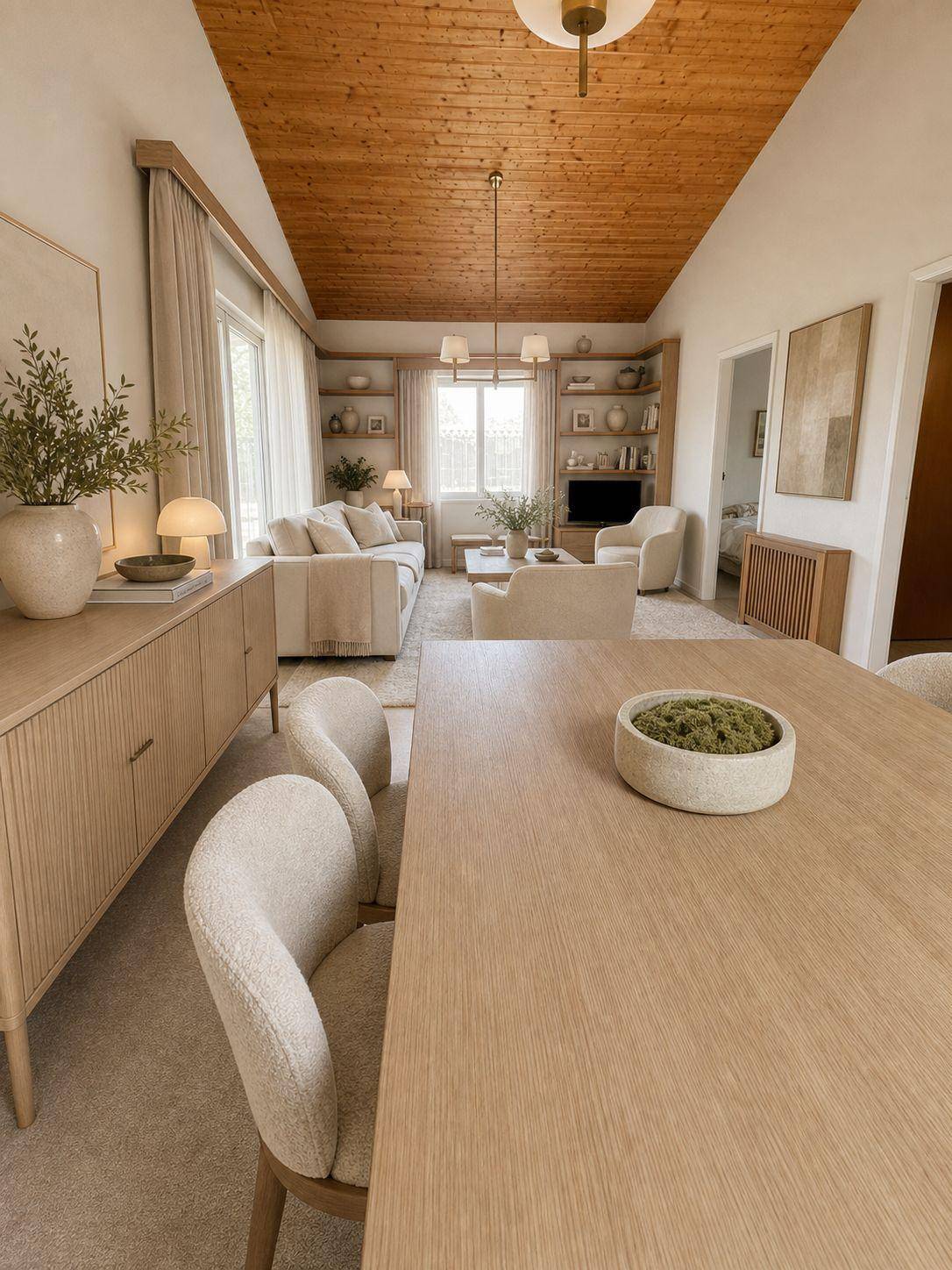 Heller, offener Wohn- und Essbereich mit Holzbalkendecke und modernen Möbeln in hellen Farbtönen.
