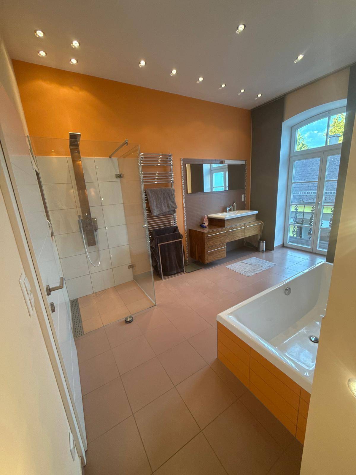 Geräumiges Badezimmer mit moderner Badewanne, begehbarer Dusche und beheiztem Handtuchhalter.