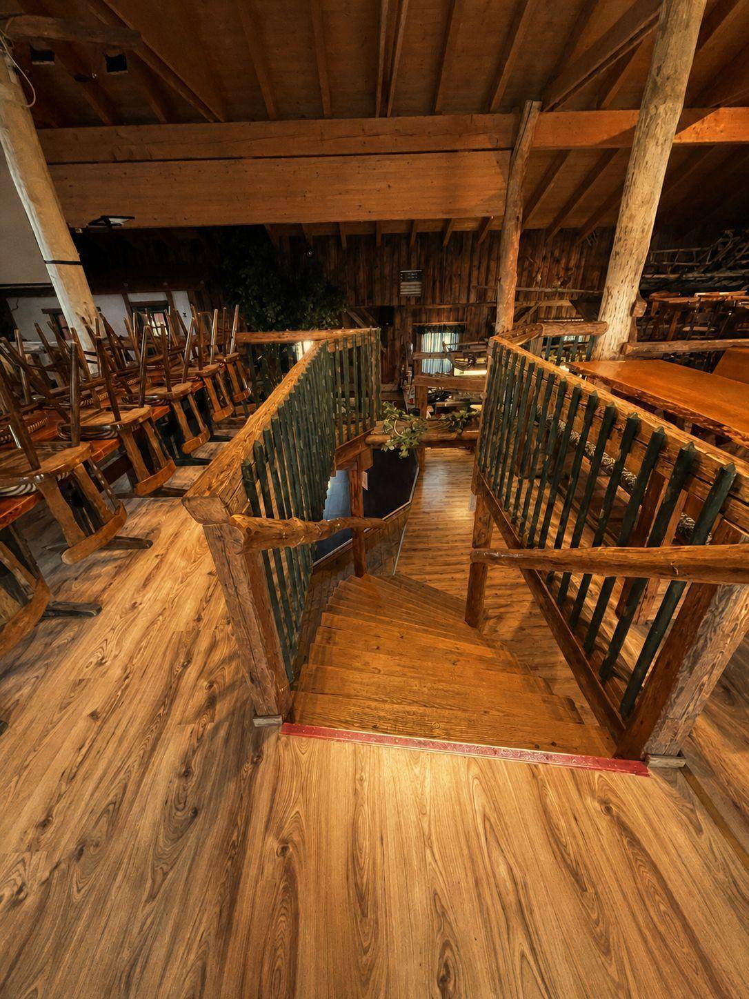 Blick auf eine Treppe und einen tiefer gelegenen Bereich in einem großen, holzvertäfelten Raum mit rustikalem Charme.