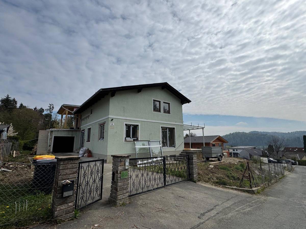 Hausansicht von der Straße mit Einfahrtstor und Baustellenbereich im Vordergrund.