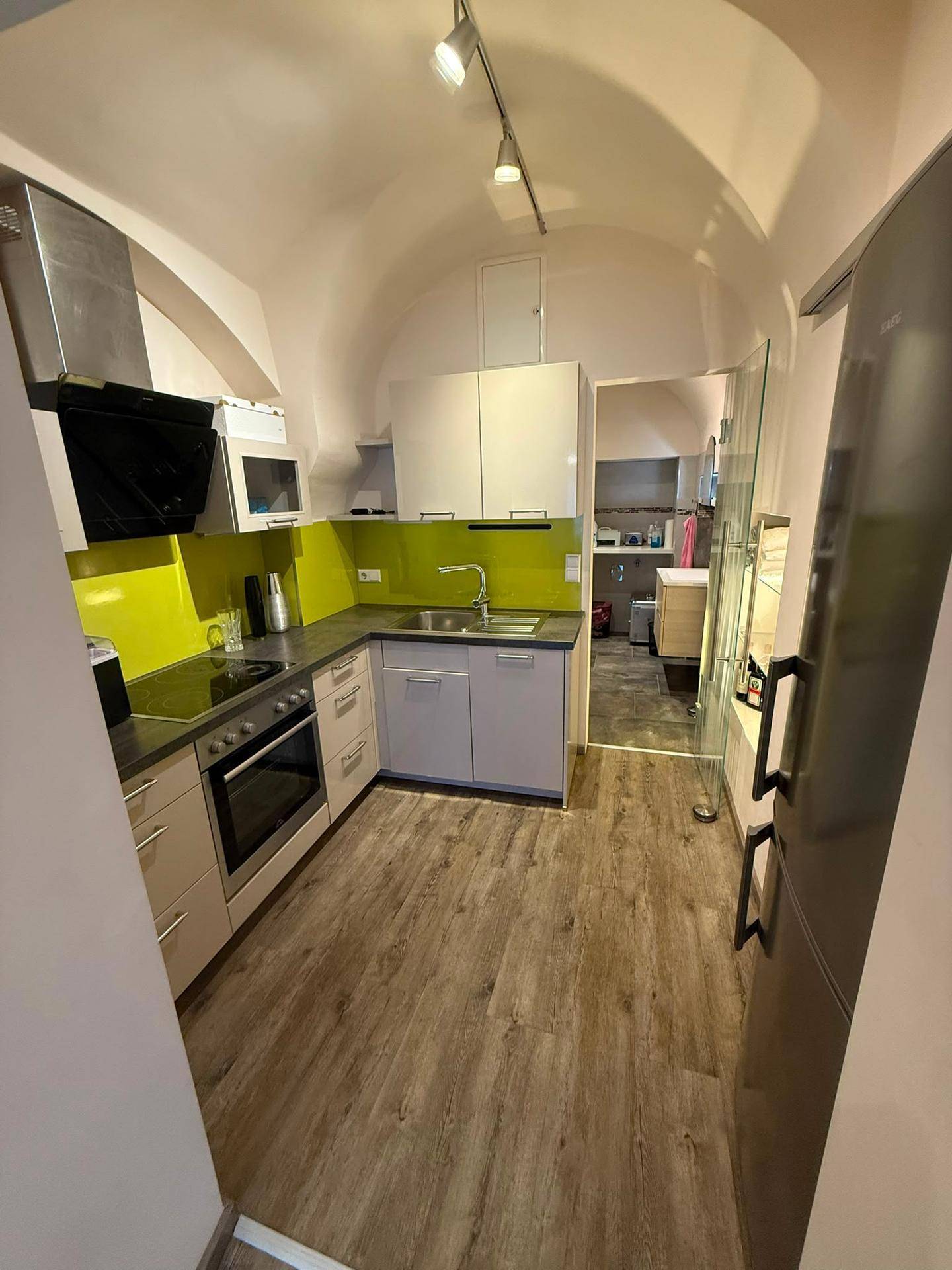 Moderne Küche mit gewölbter Decke, gelber Rückwand und integrierten Geräten.