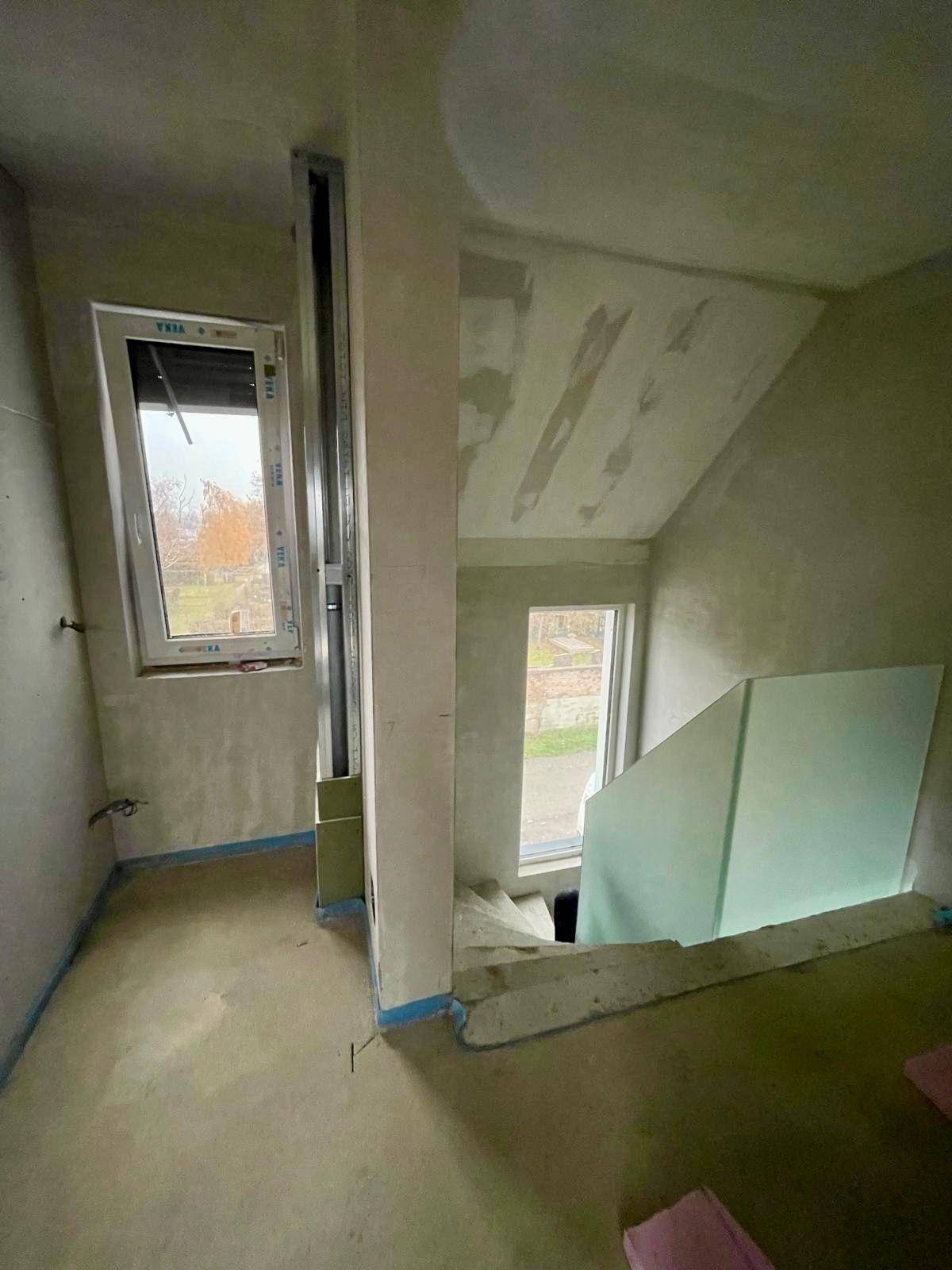 Unfertiger Flur mit Treppenaufgang und Fenster, bereit für den weiteren Ausbau.