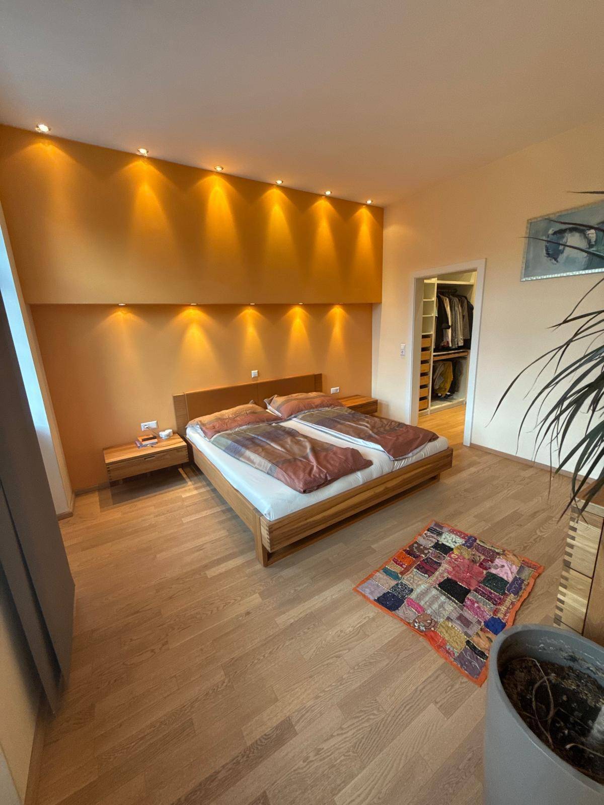 Helles Schlafzimmer mit Holzboden, Doppelbett und direktem Zugang zu einem begehbaren Kleiderschrank.