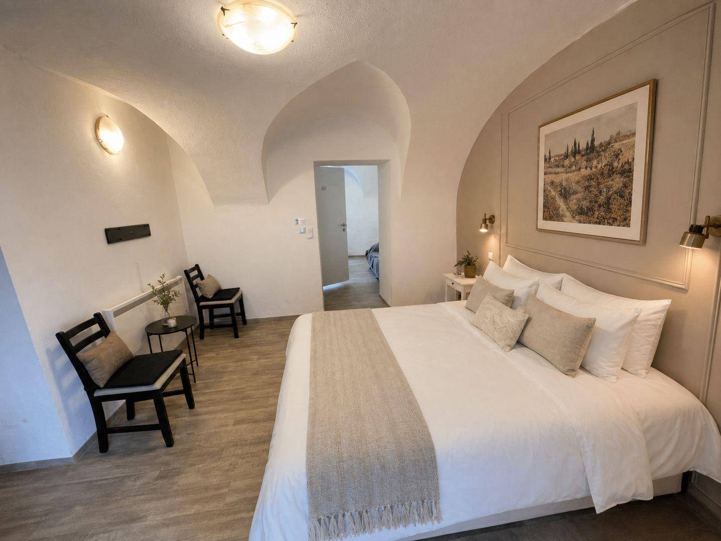 Helles Schlafzimmer mit gewölbter Decke, Holzboden und stilvoller Einrichtung.