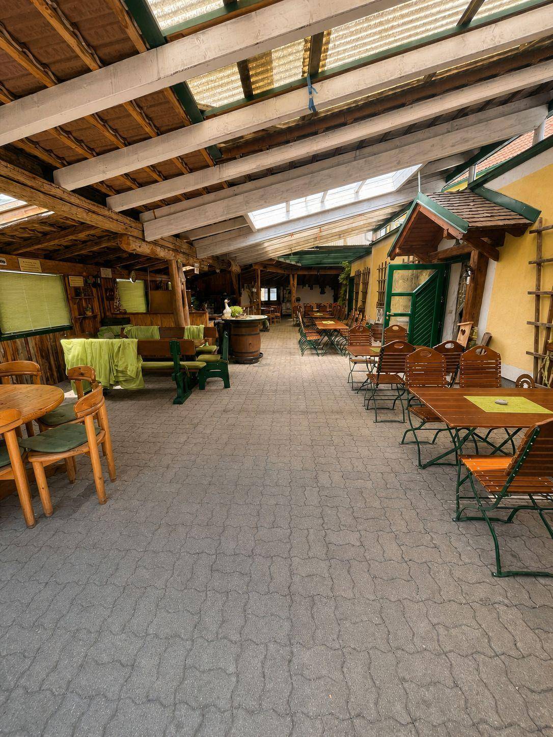 Überdachter Außenbereich mit zahlreichen Holztischen und Bänken, ideal für größere Gruppen.