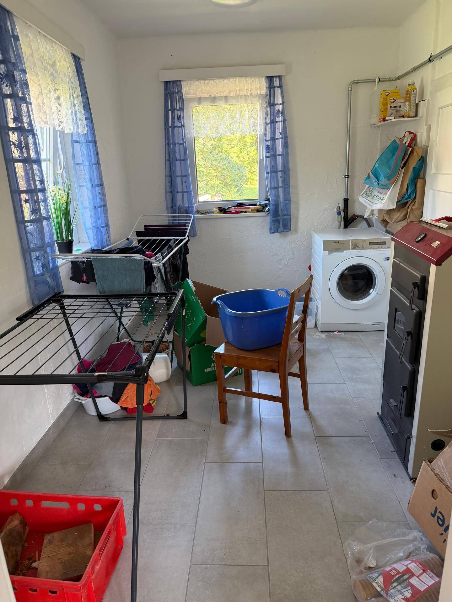 Hauswirtschaftsraum mit Waschmaschine, Trockengestellen und Fliesenboden.
