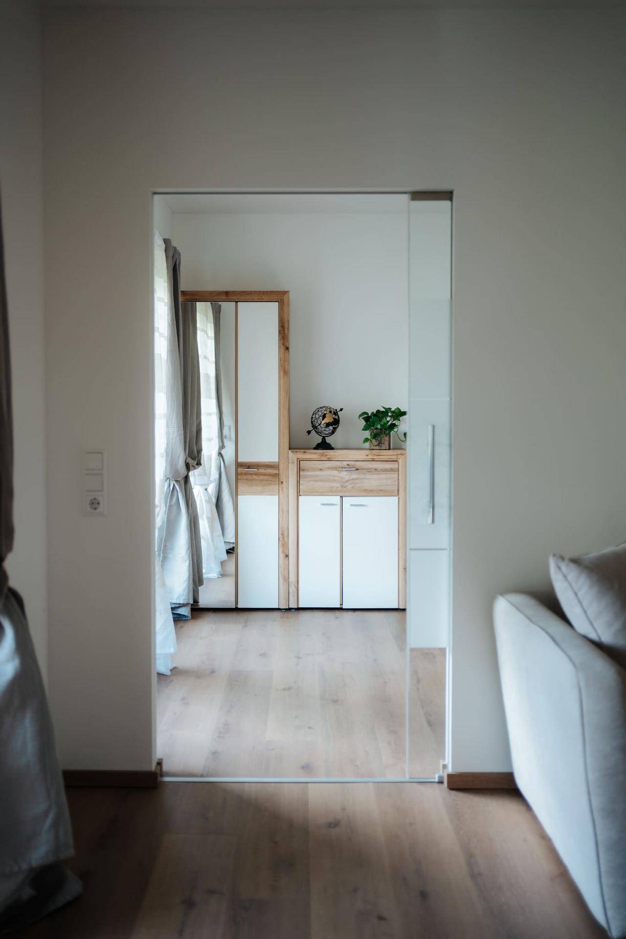 Heller Flur mit Holzboden und einem modernen Schrank mit Spiegel, der zu weiteren Räumen führt.