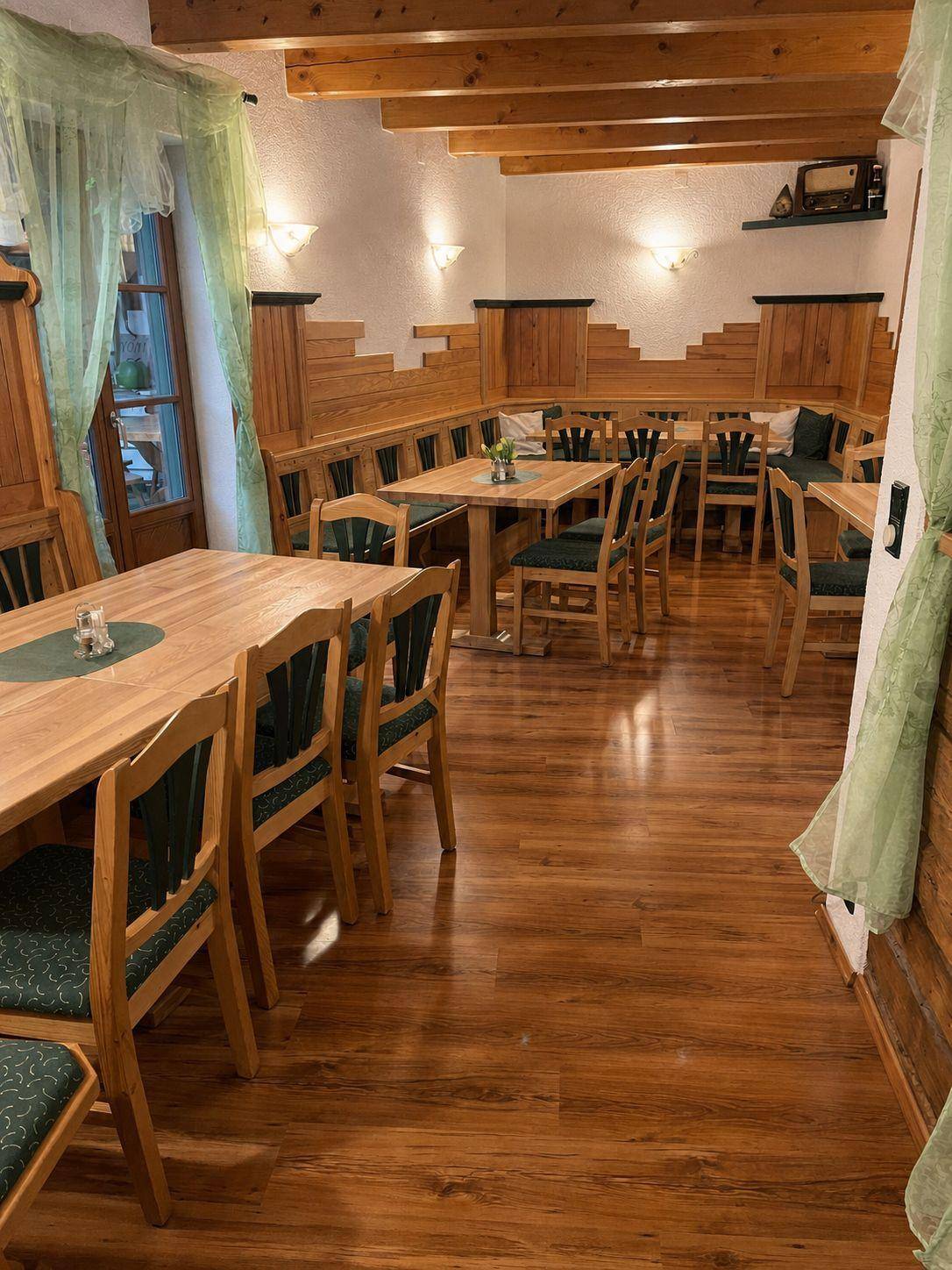Heller Essbereich mit Holztischen, Bänken und grünen Akzenten, gemütlich und traditionell.