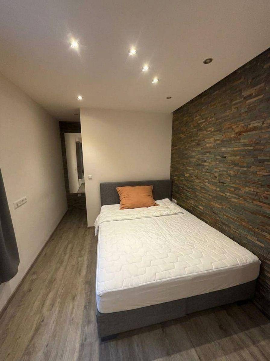 Gemütliches Schlafzimmer mit Einzelbett und einer dekorativen Steinwand.