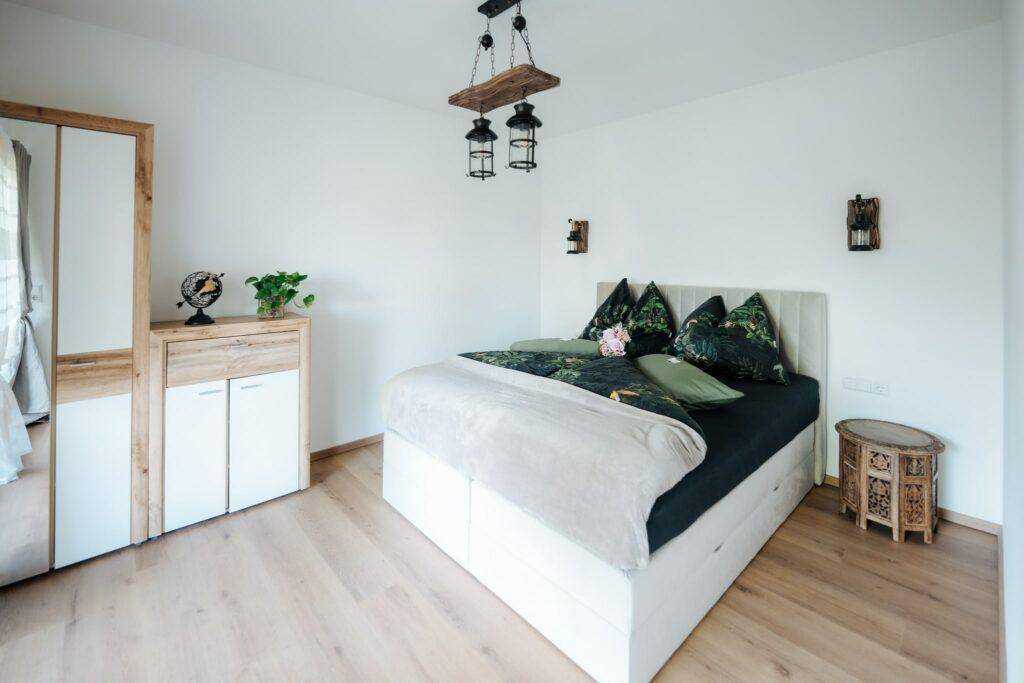 Helles Schlafzimmer mit Holzboden, modernem Bett und Schrank mit Spiegel, bietet viel Stauraum.