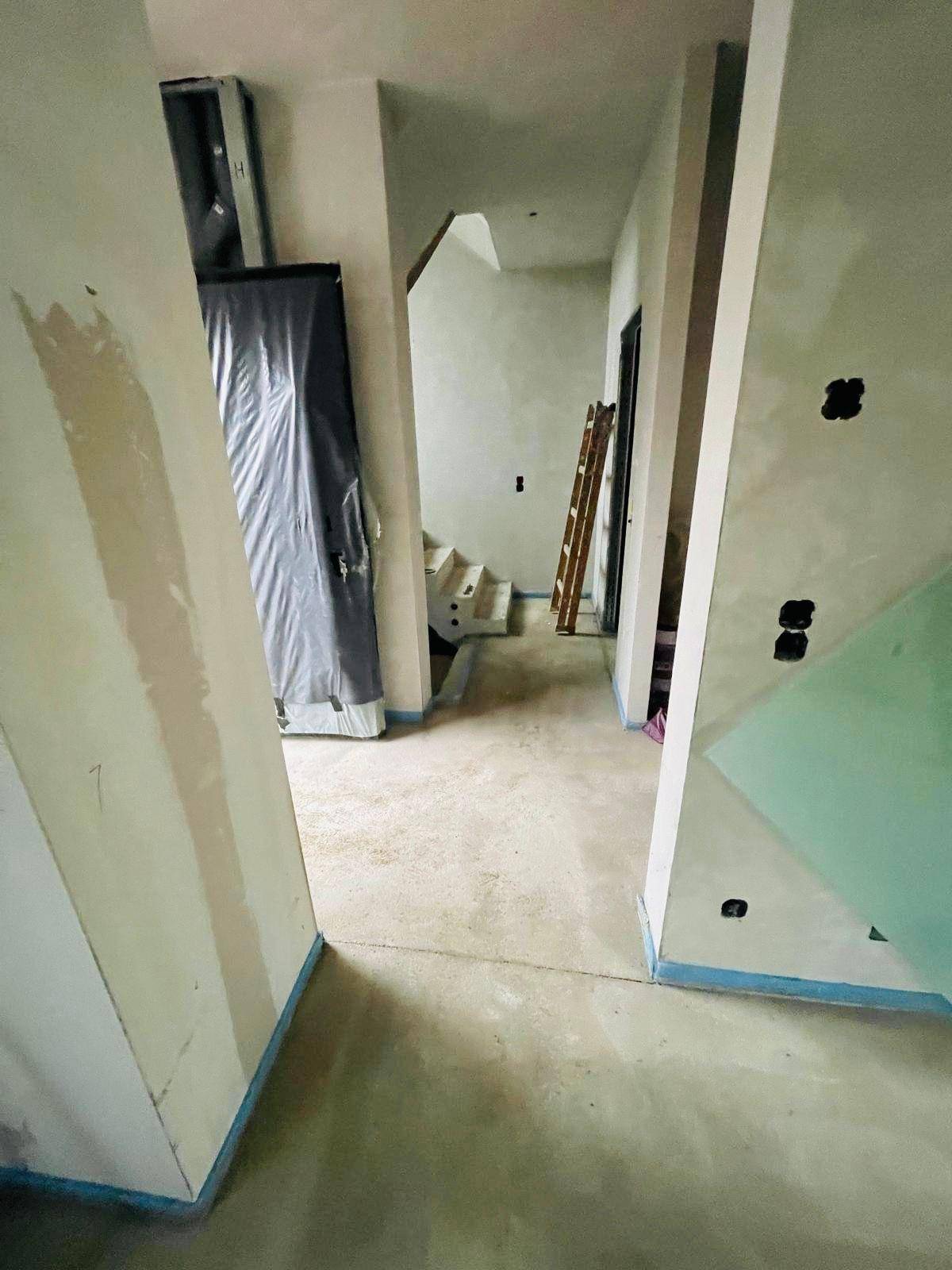 Unfertiger Flur mit Treppenaufgang und Estrichboden, bereit für den weiteren Ausbau.