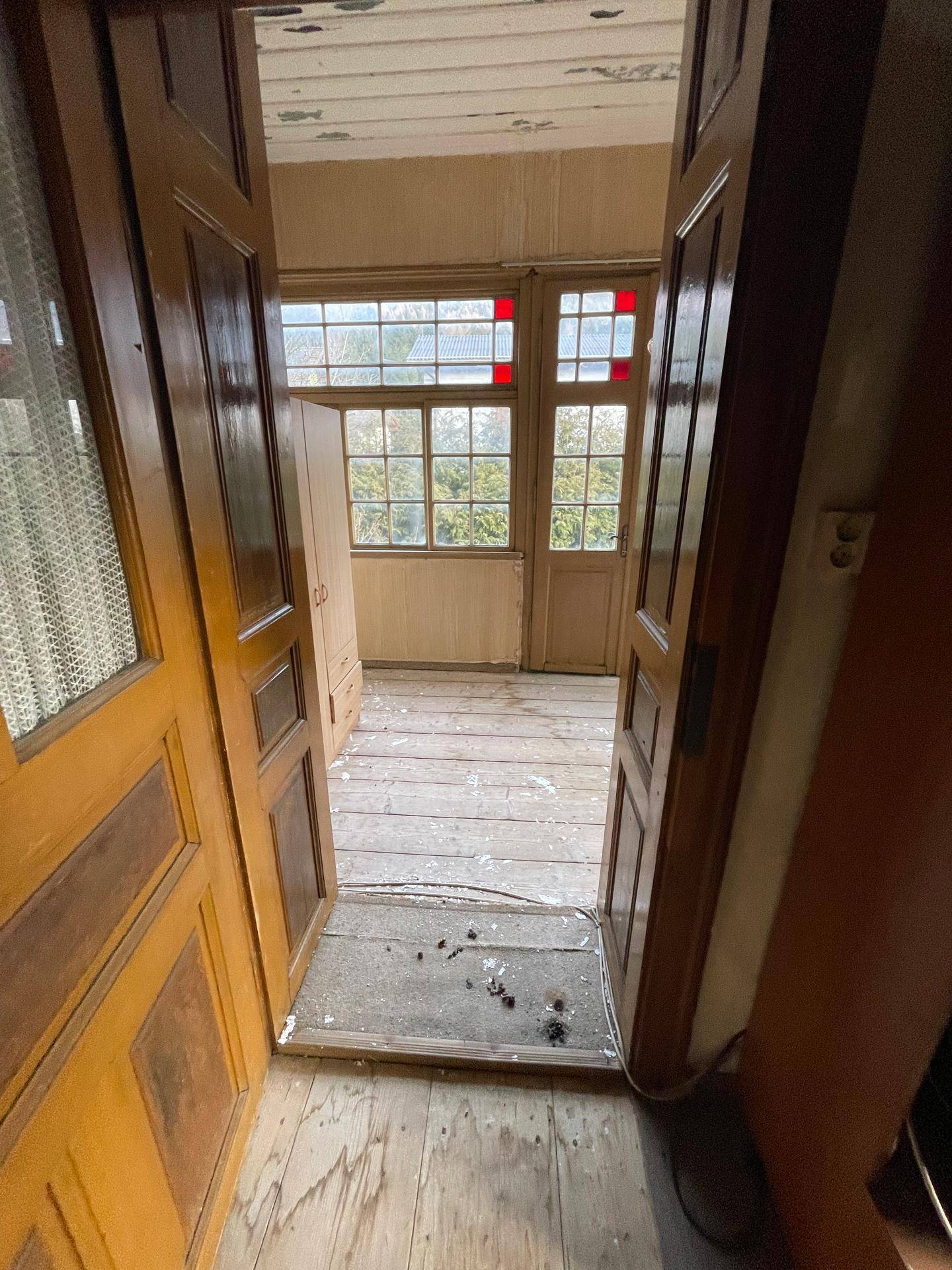 Verglaster Raum mit Holzplankenboden und vielen Fenstern, der als Wintergarten oder Loggia dienen könnte.
