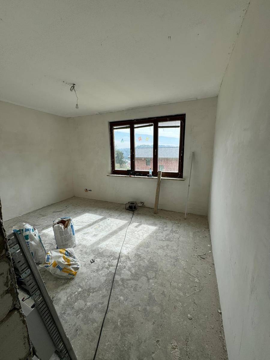 Schlafzimmer im Rohbau mit Fenster und Blick auf die Landschaft, bereit für die Fertigstellung.