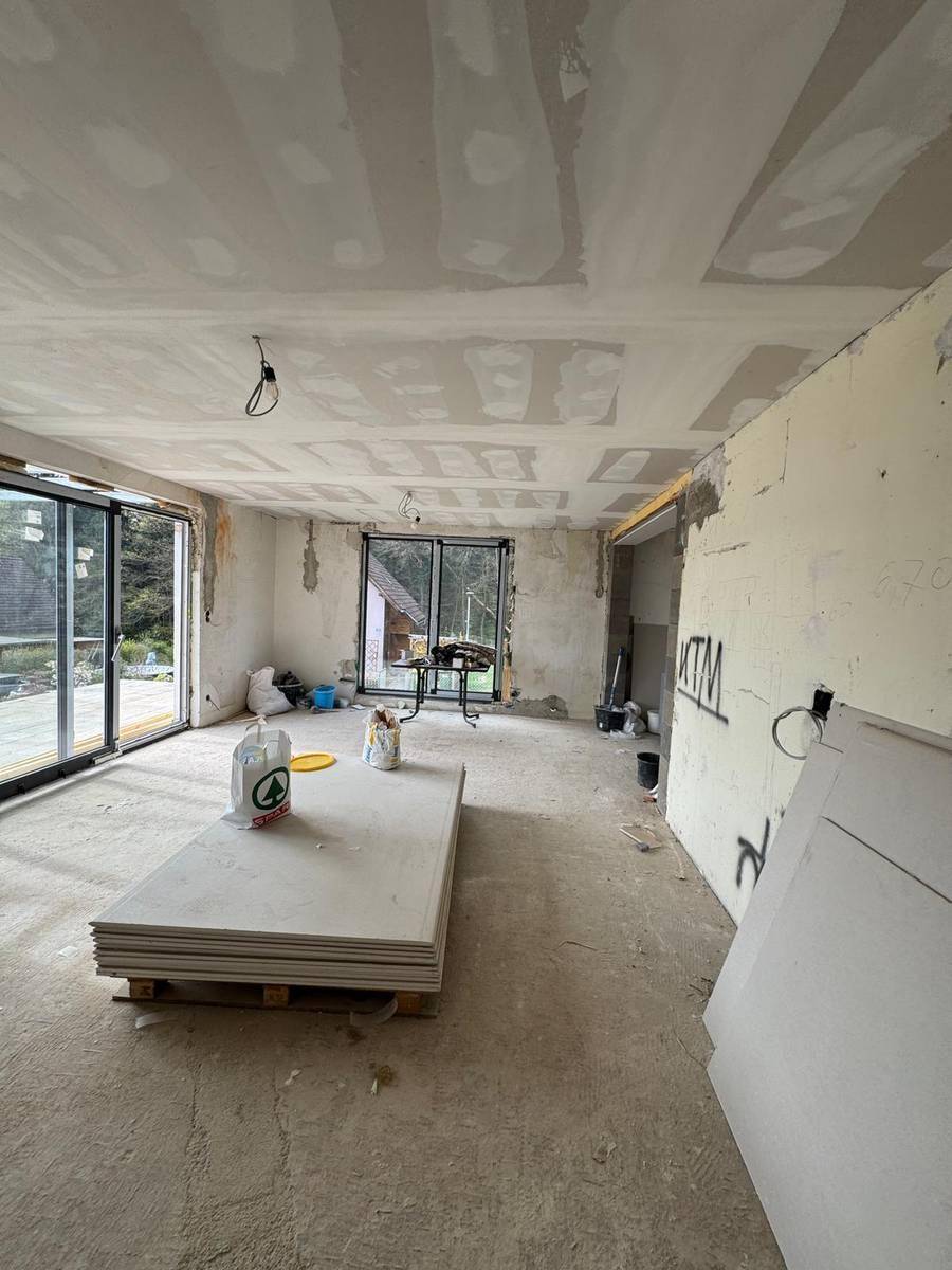 Geräumiger Wohnbereich im Rohbau mit großen Fensterfronten und Blick ins Freie, bereit für die Innengestaltung.